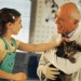 Little girl petting cat in veterinarian's arms